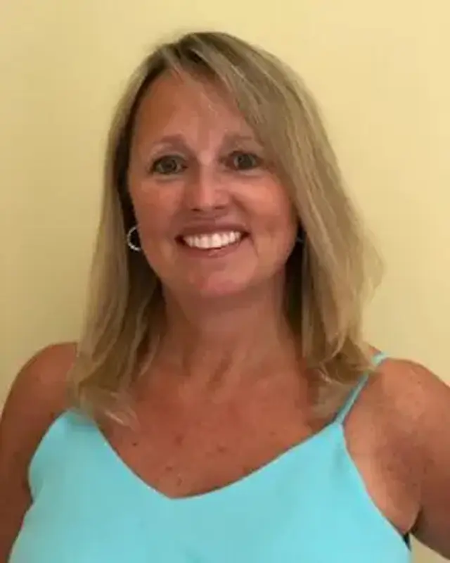 A woman in blue shirt smiling for the camera.