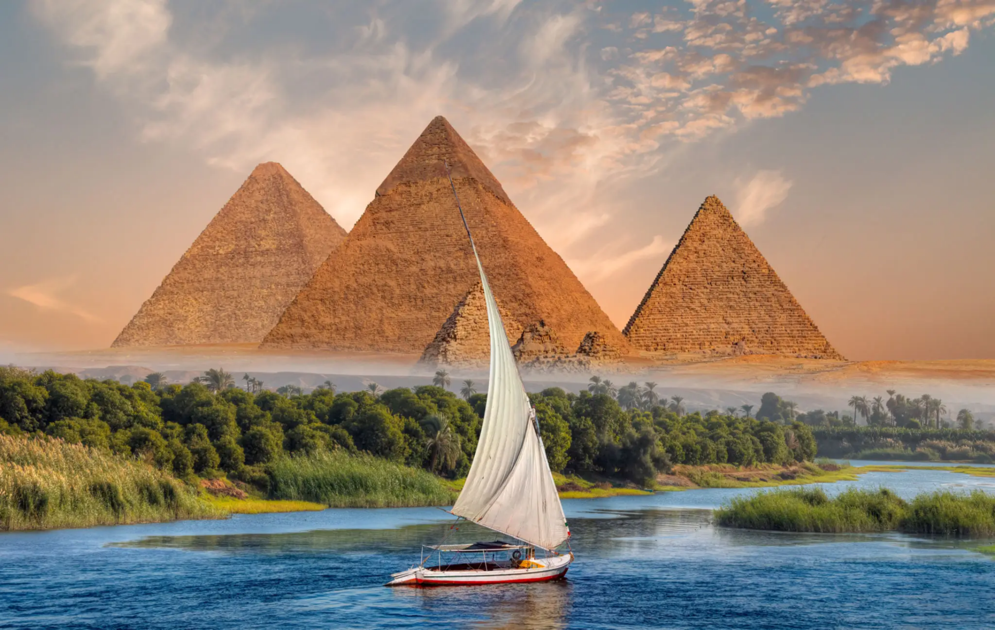 blob-4d66ec1 A sailboat sailing on the water near some pyramids.