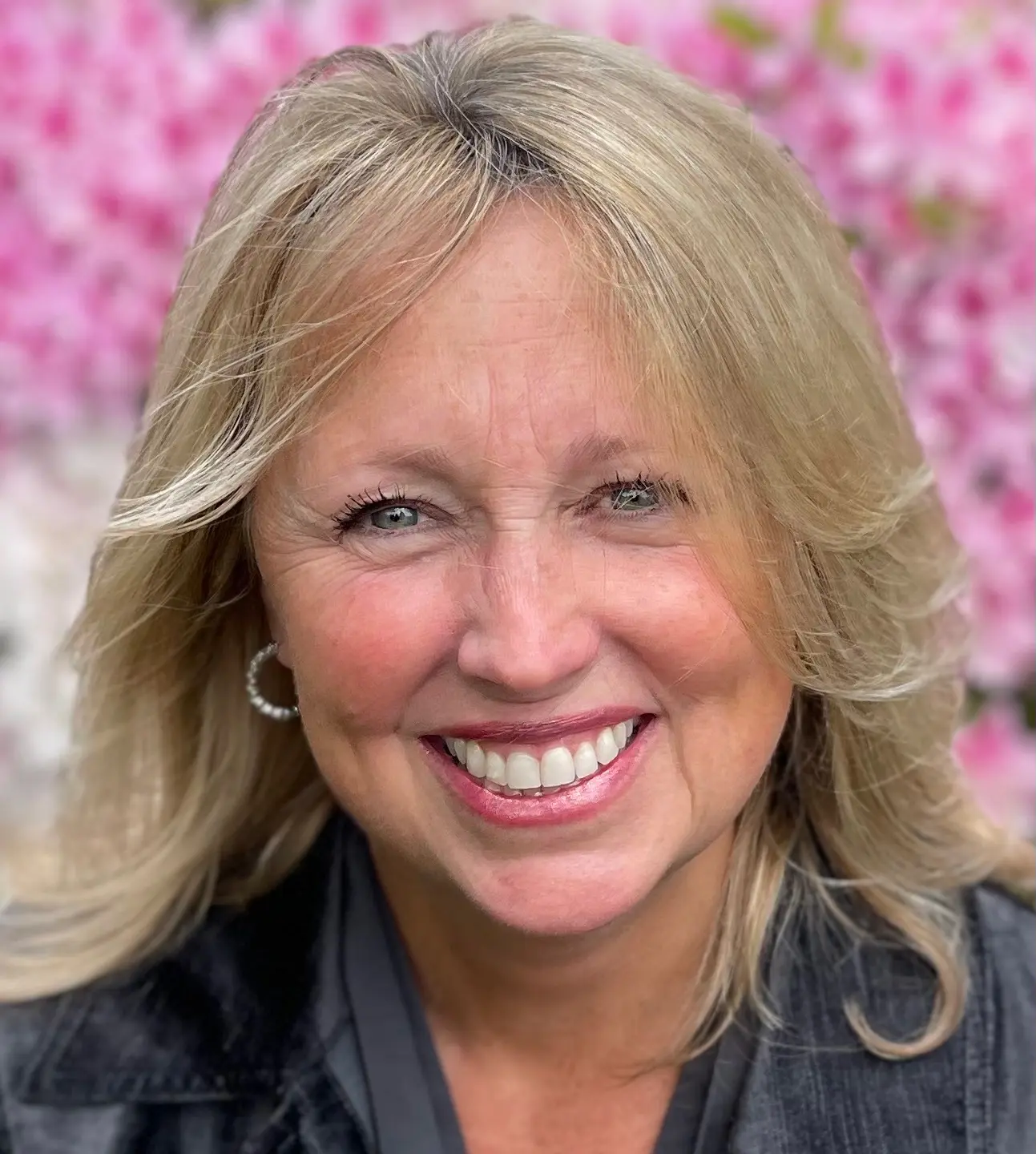 A woman with blonde hair and blue eyes smiling.